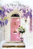 The photograph portrays a quietly enchanting doorstep in Crofton Park, styled as if for a heartfelt housewarming delivery. At its centre, a pale pink front door, painted in a gently muted blush, stands out against clean white walls that reflect the soft afternoon light drifting across SE4. Above the frame and gently trailing down one side, wisteria spills in generous cascades, every spray a mix of lavender, lilac, and subtle silvered mauve. The blossoms form a loose canopy, brushing against a softly coloured shutter and casting dappled shadows on the wall, reminiscent of the leafy calm near Crofton Park station or the walkways by Hilly Fields. Just in front of the threshold, sitting squarely on the stone step, is a vintage-style grey metal bucket overflowing with white and cream roses. The roses are plump and velvety, some fully open to reveal swirling hearts of petals, others still cupped and expectant. Sprigs of soft green foliage weave between the blooms, giving the arrangement depth and a touch of natural wildness. A delicate pink ribbon, tied neatly around the bucket, provides a final romantic detail; its satin tails rest lightly against the step, echoing the soft pastel tones of the door. The interplay of light and shade, colour and texture, creates a mood of hopeful tranquillity, as if this arrangement has been placed moments before the new owners arrive home from nearby Brockley Road with their final box. It feels like a gentle blessing for a fresh chapter in Crofton Park-a floral embrace that says welcome, congratulations, and may this house be filled with warmth.